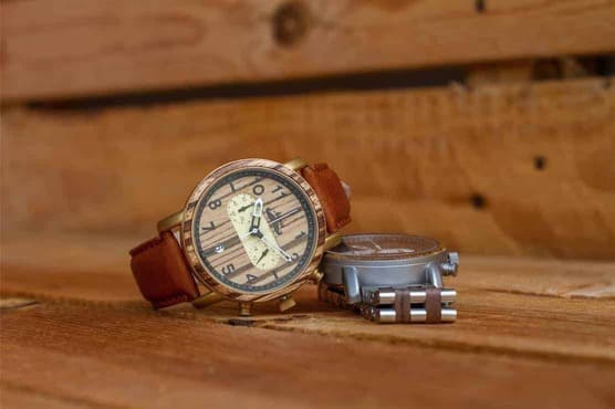 montres homme en bois, une avec son bracelet cuir et l'autre avec son bracelet bois et métal, sur un fond de palettes en bois